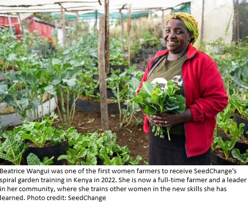 Beatrice Wangui in her spiral garden holding leafy vegetables 