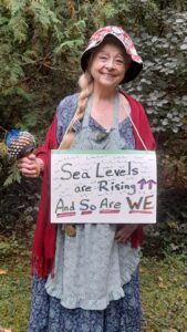 Seniors for Climate Action - Norah holding a sign that says "Sea levels are Rising And So Are We"