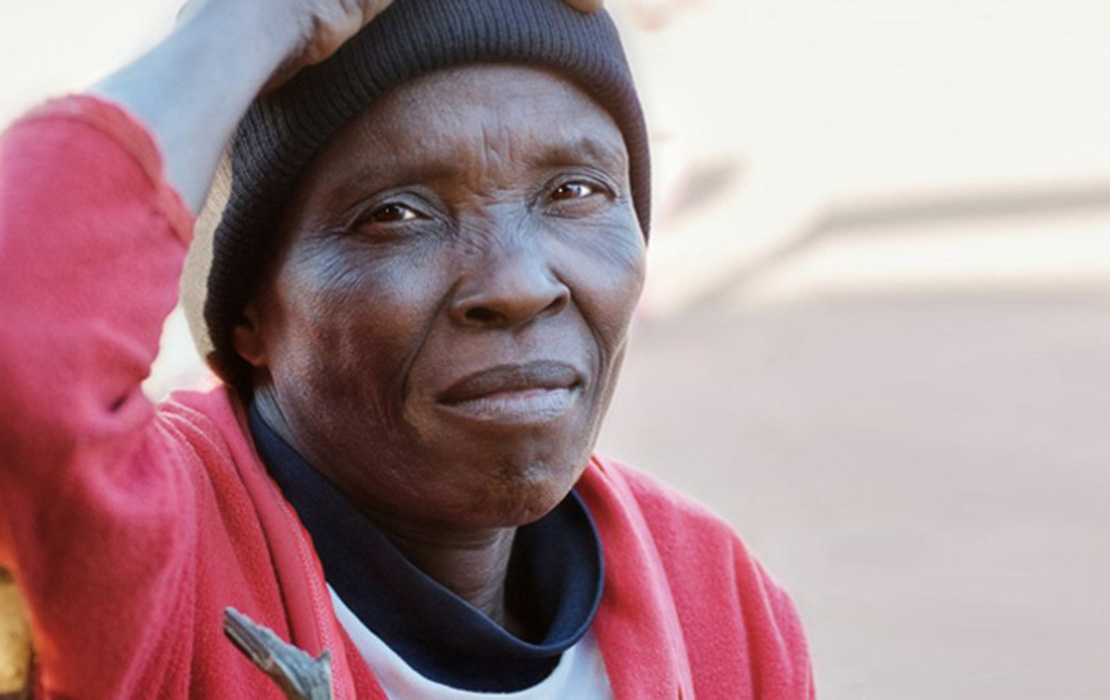 African woman in a red sweater with one hand on her head