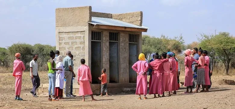 School children observe outdoor toilets
