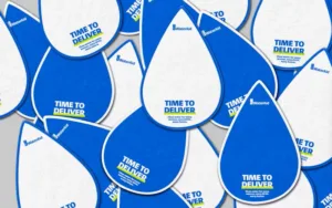 Pile of white and blue paper water droplets with Time to Deliver printed on them