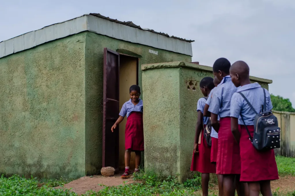 School girls wait their turn outside girls' toilet in Nigeria